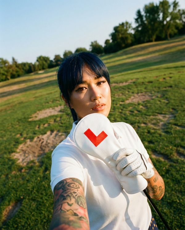 Mika holding Learner Driver on a golf course in golden hour light wearing white golf attire 1